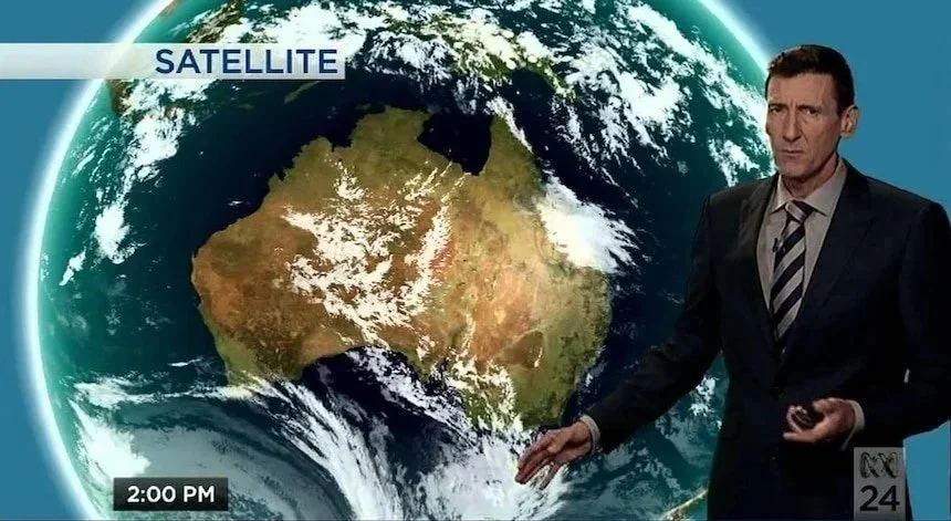A weather presenter Graham Creed standing in front of a digital map of Earth showing Australia from space, with satellite data and weather patterns, on a news broadcast at 2:00 PM.