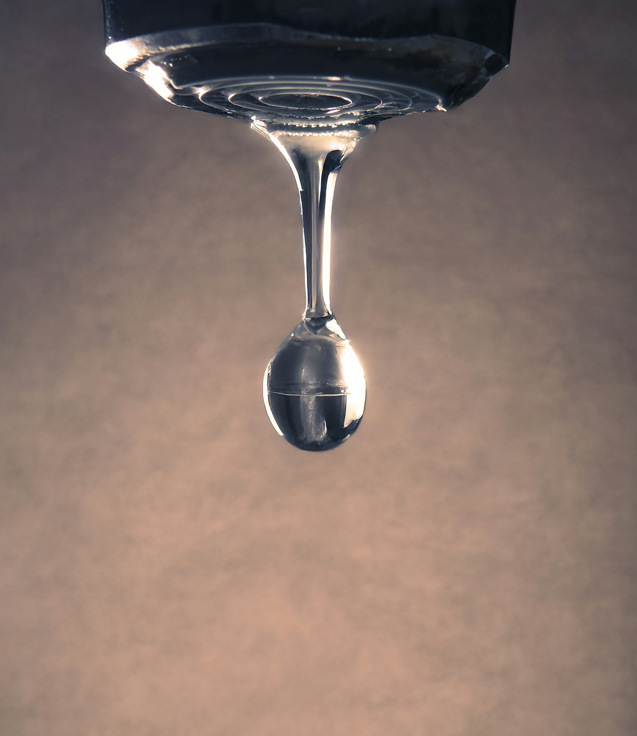Close-up of a water droplet hanging from a faucet.