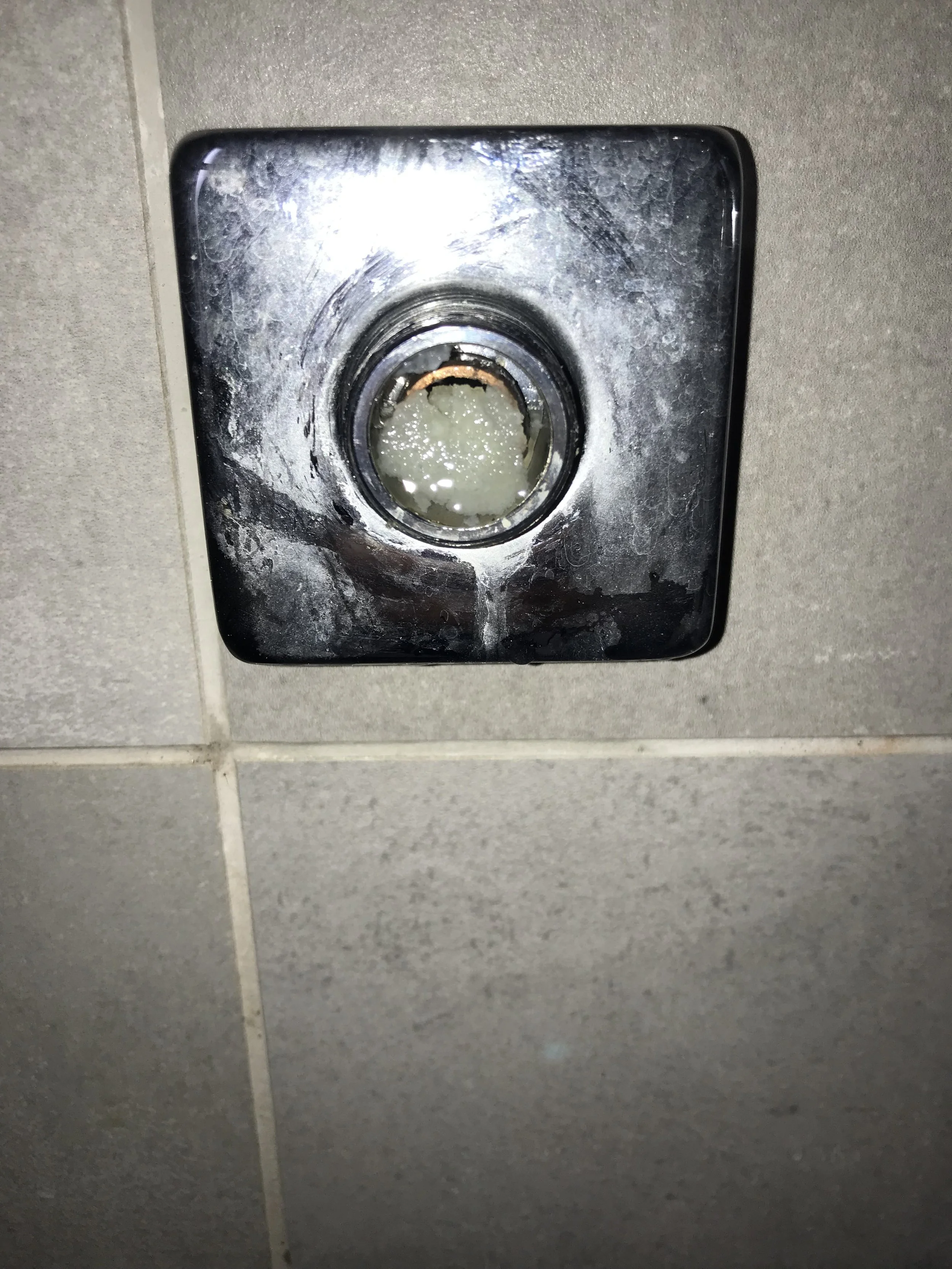 A wall-mounted paper towel dispenser with the cover removed, exposing the inner mechanics and paper towel roll inside.