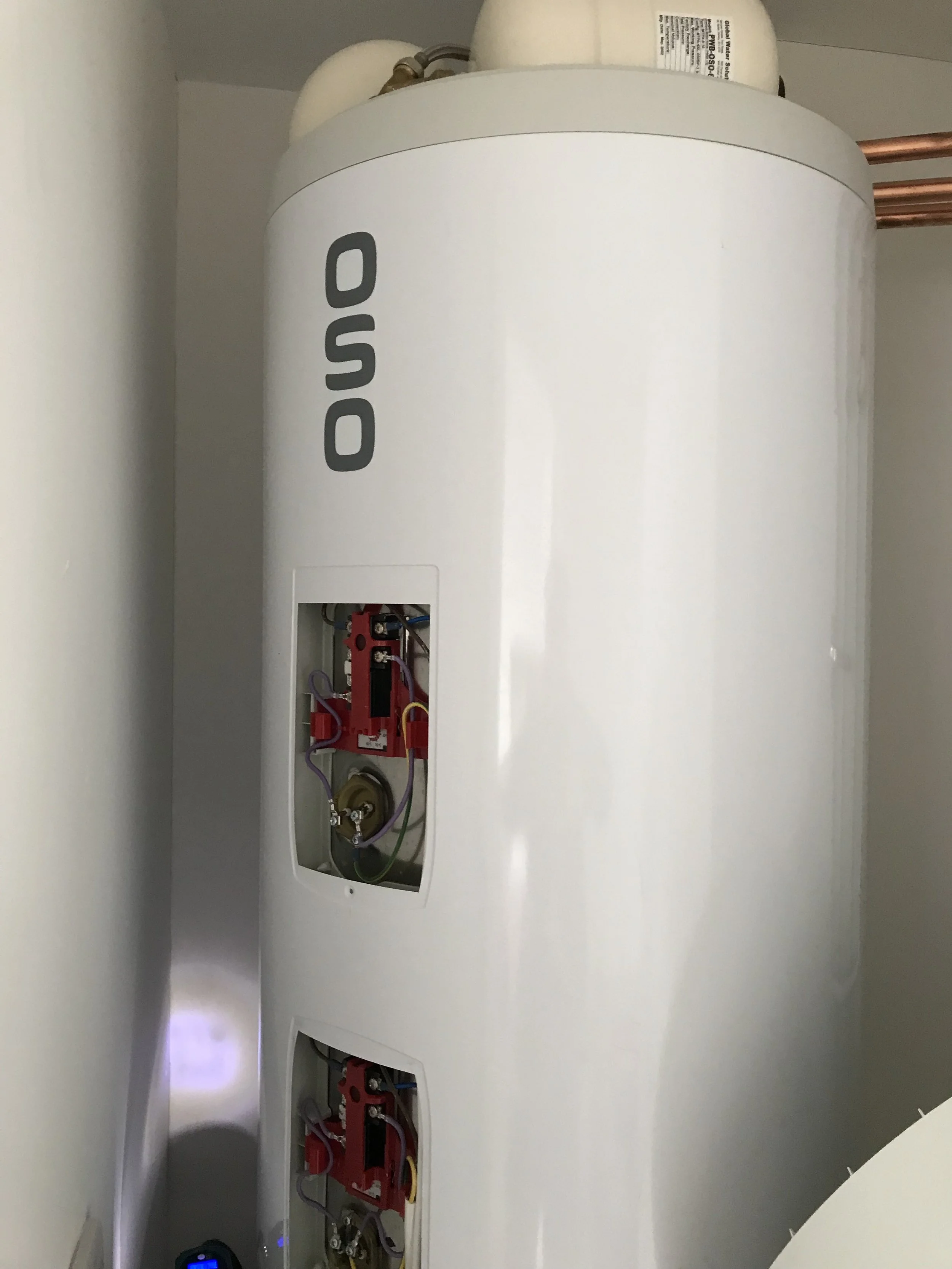 Close-up of a white AO Smith water heater with a section open to reveal electrical wiring and components inside.