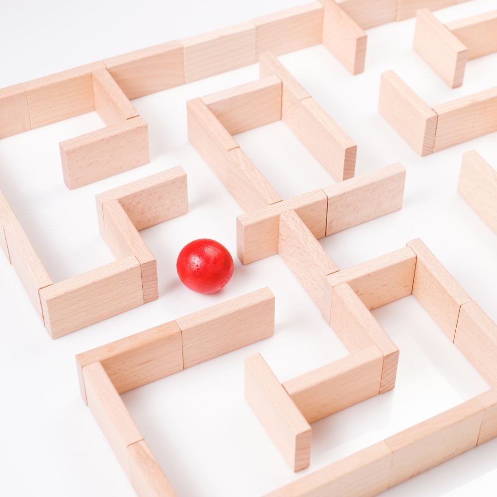 A wooden maze with a red ball inside.