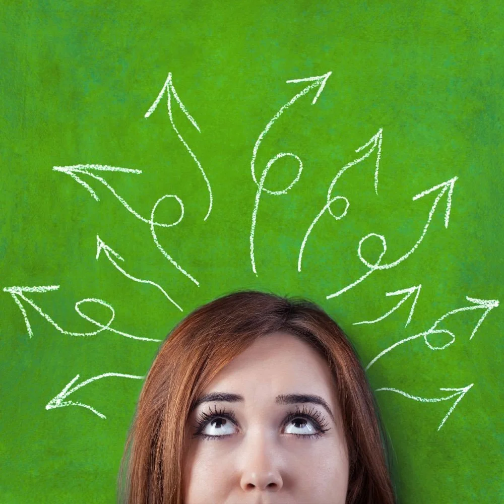 A woman with brown hair looking up at a green background with white chalk arrows pointing outward.