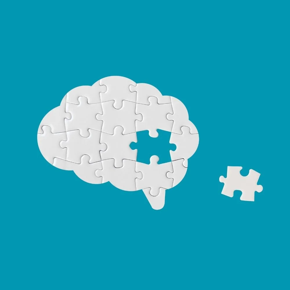 A puzzle in the shape of a brain, with one piece missing and a separate piece next to it, on a blue background.