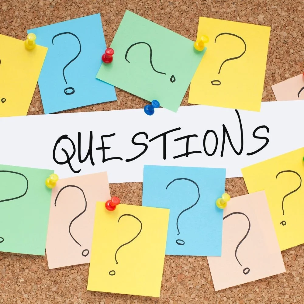 Colorful notes with question marks pinned to a corkboard and a white paper with the word 'Questions' written in black.