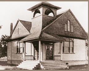 Old black and white photo of a large Victorian-style house with a tower, front steps, and multiple windows.