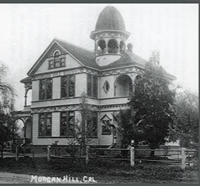 Black and white photo of Morgan Hill, California, with a large historic Victorian-style house featuring a prominent dome on top, surrounded by trees and a wooden fence.