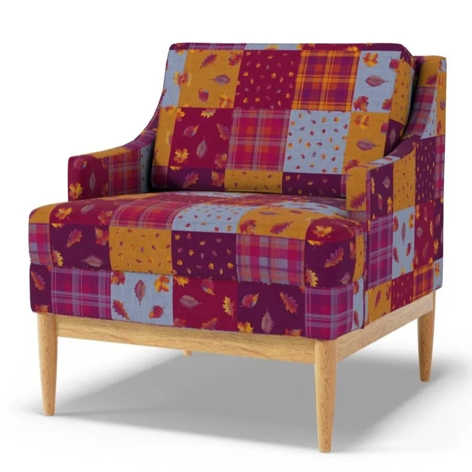 Upholstered armchair featuring the Falling Leaves patchwork cheater‑quilt design by Aitch Jay Designs, combining autumn leaf prints and plaid squares in warm burgundy, mustard, blue and red tones, for a cozy, seasonal home decor look.