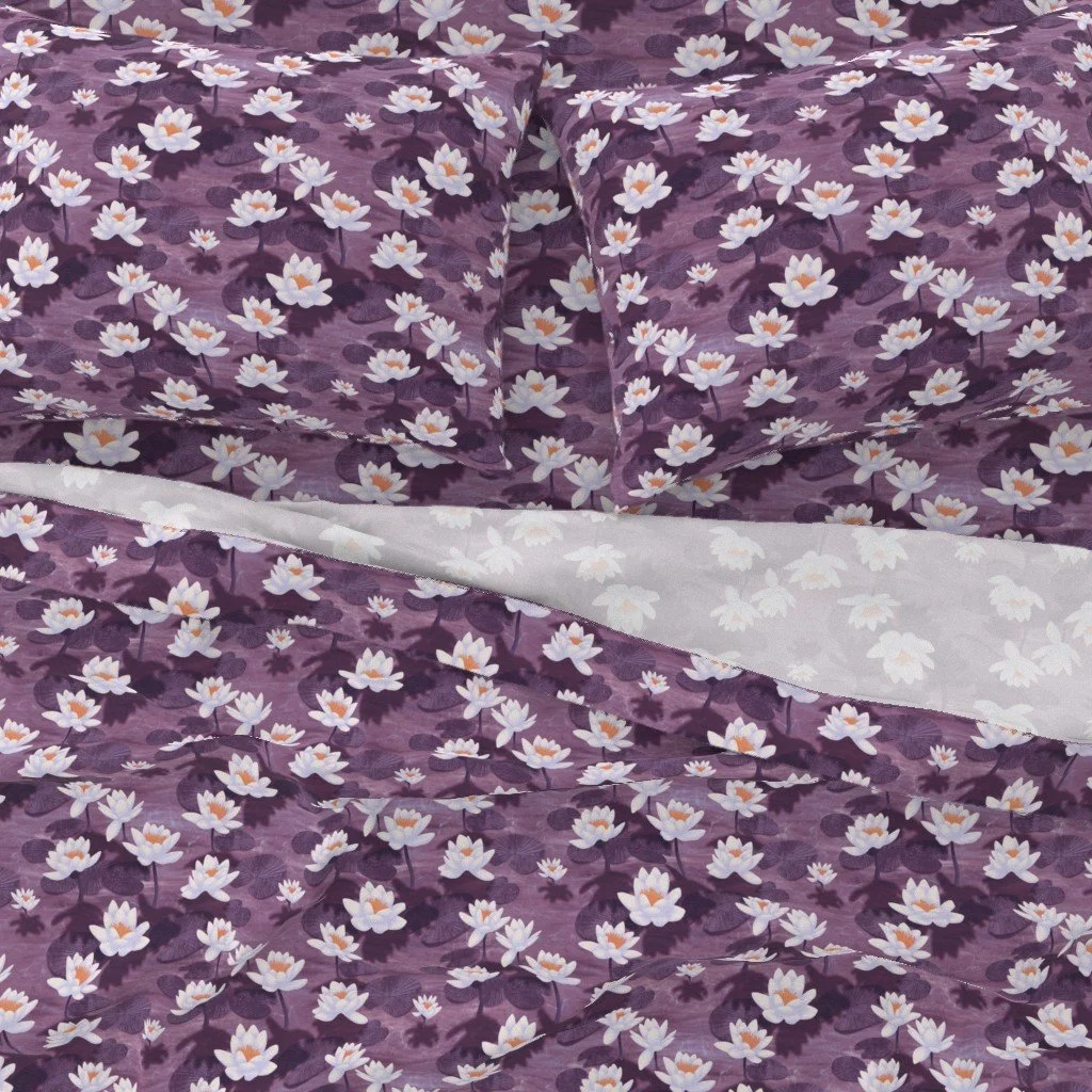 Lotus Blossom Drift by Aitch Jay Designs — a repeating lotus‑flower pattern in soft pinks and whites on a rich purple background, shown on bedding to highlight the delicate, serene floral design.