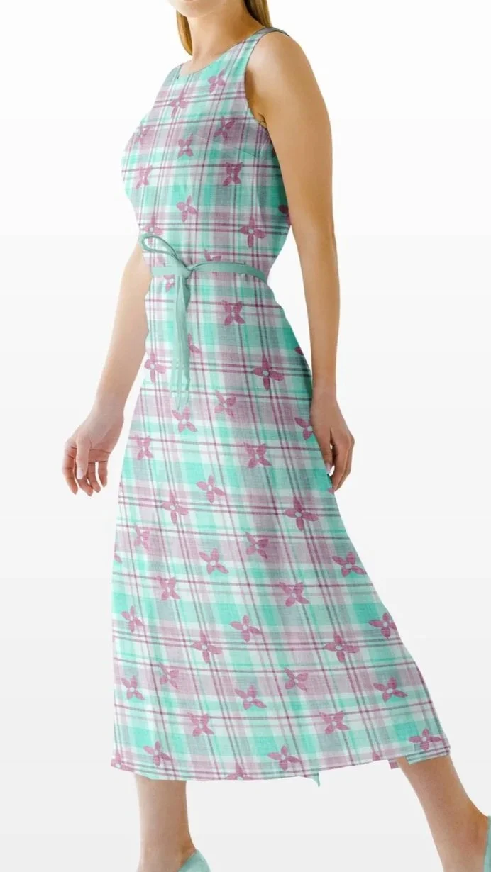 A woman wearing a sleeveless, pastel-colored plaid maxi dress with pink floral and butterfly patterns, standing against a white background.