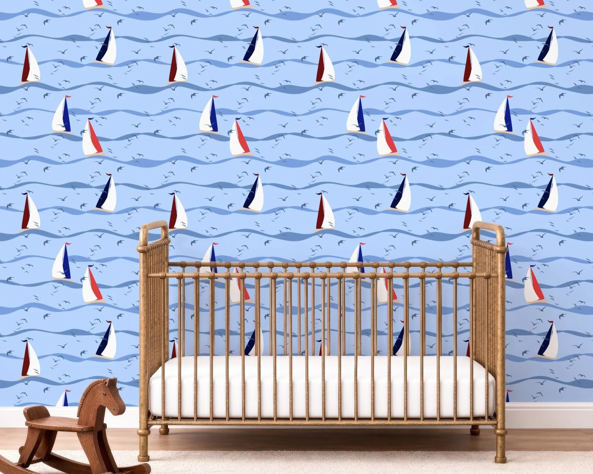 Sail Away Storybook Collection by Aitch Jay Designs — whimsical sailboat and wave repeat in soft coastal blues with seabirds sihouettes, shown on a nursery feature wall to create a gentle, imaginative ocean‑storybook space.