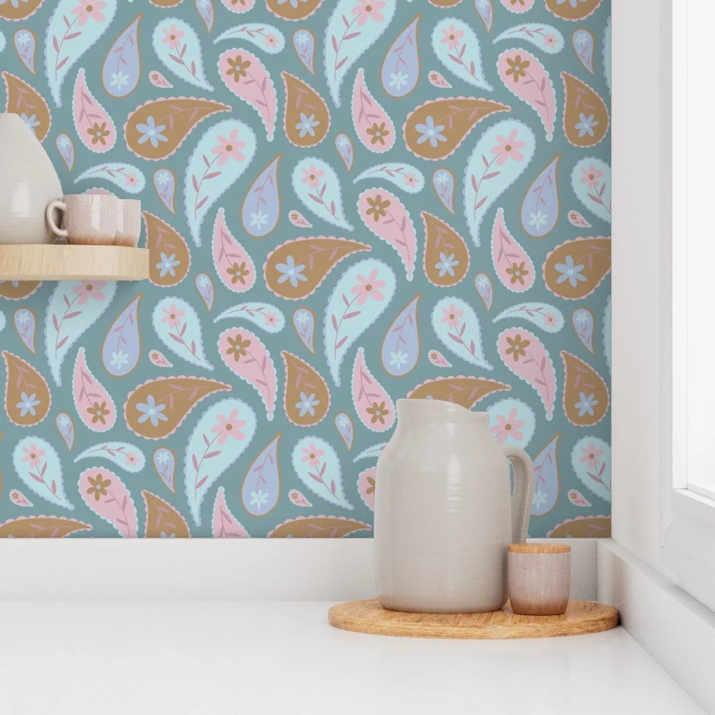 Decorative wall with a colorful paisley floral pattern in pastel shades of pink, blue, and brown, featuring a white pitcher and a small cup on a wooden tray near a window.