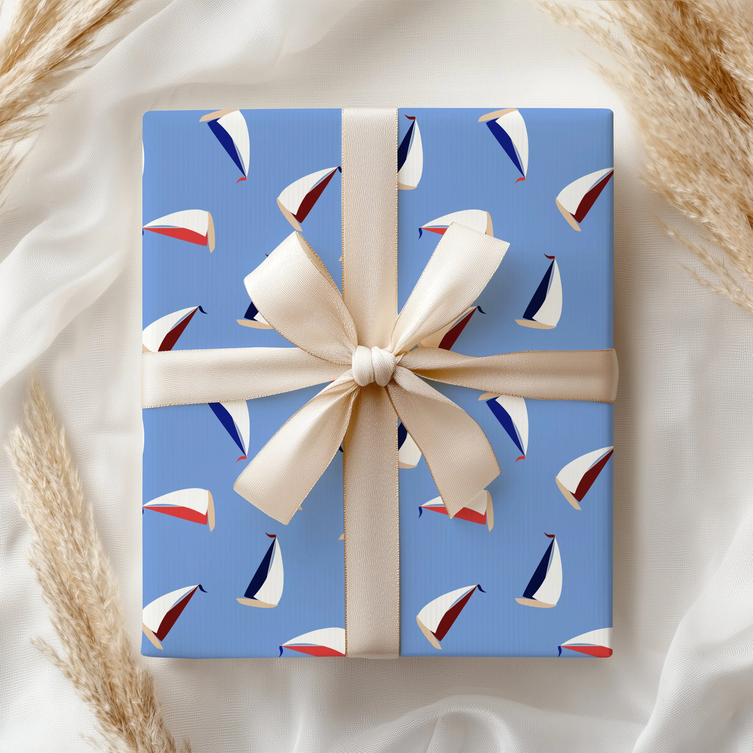 Sail Away Storybook Collection by Aitch Jay Designs — light blue tossed sailboat repeat with red, white and navy accents, shown on as wrapping paper on a gift, for a refined coastal celebration aesthetic.