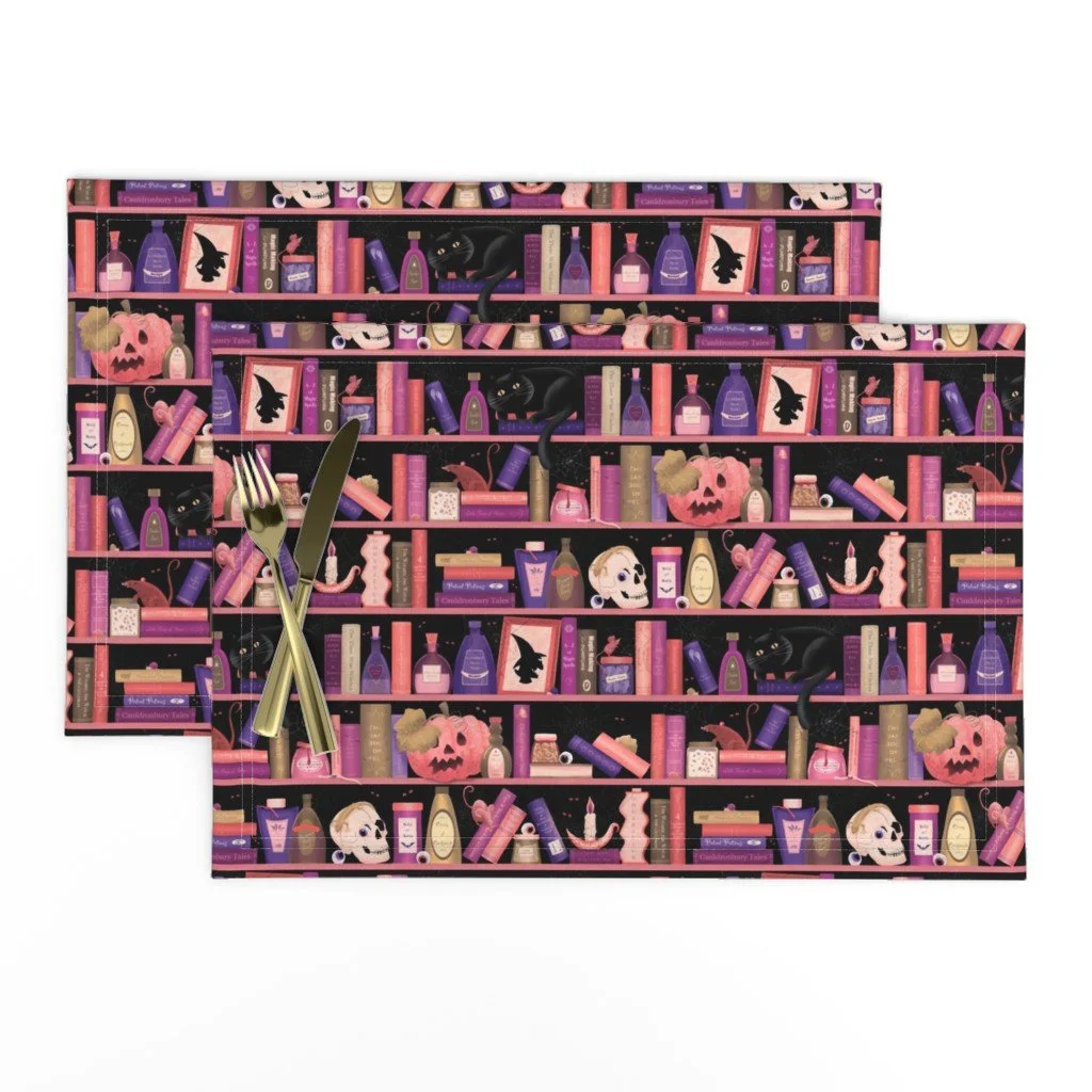 Two Halloween-themed placemats featuring a pattern of bookshelves with potion bottles, skulls, black cats, and pumpkins in purple, pink, and beige colors.