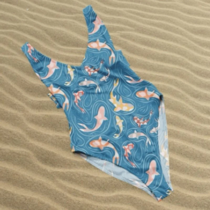 A detailed view of the Koi Paisley koi‑and‑water repeat pattern in orange, white and yellow tones on blue, presented on a swimsuit to demonstrate application for apparel and product design