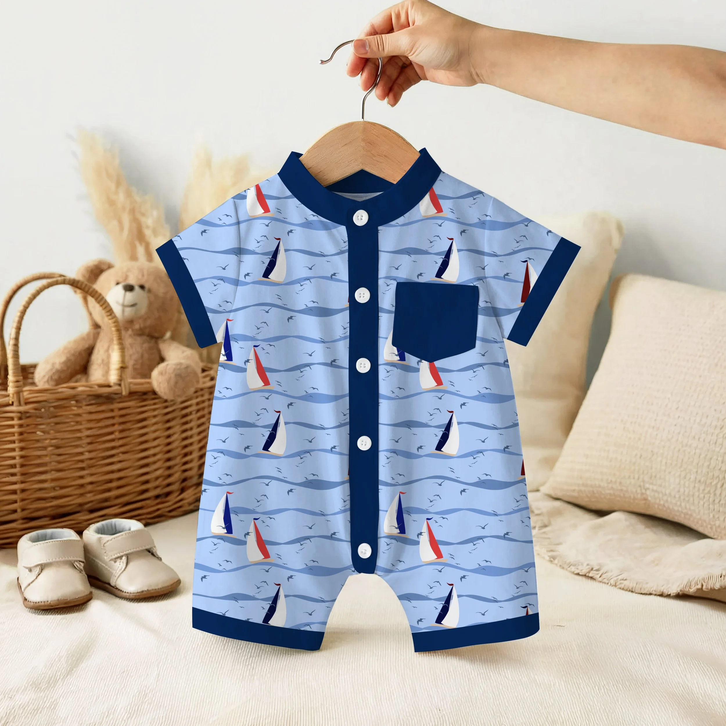 Sail Away Storybook Collection by Aitch Jay Designs — light blue sailboat and wave repeat with navy trim, shown on a baby romper to highlight charming coastal children's apparel.