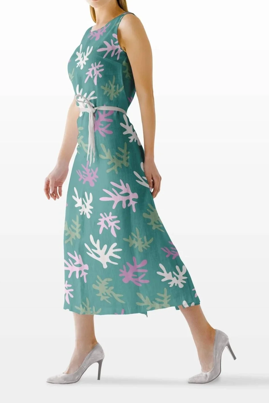 Woman wearing a sleeveless teal dress with pink, white, and beige abstract coral patterns, paired with gray high heels.