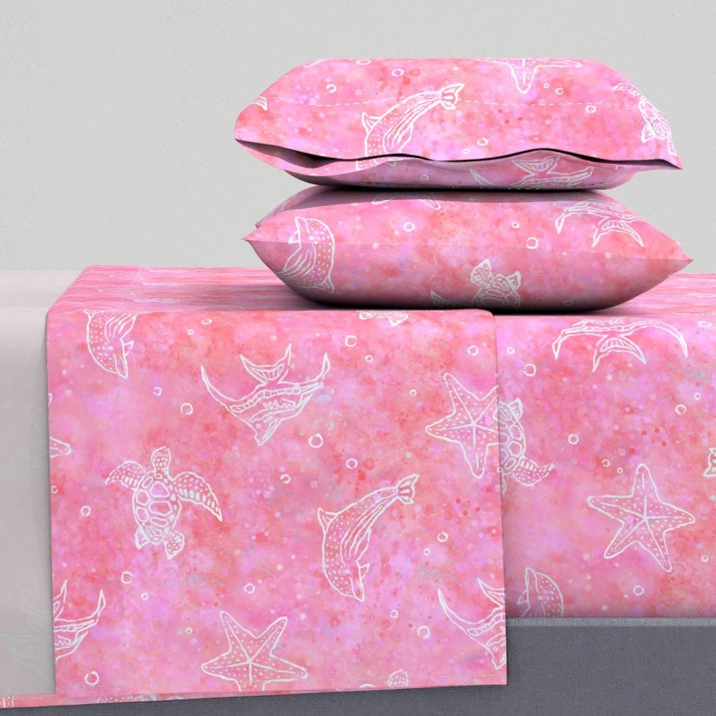 Pink bedsheets and pillowcases with a white ocean animal print, including starfish, crabs, fish, and turtles.