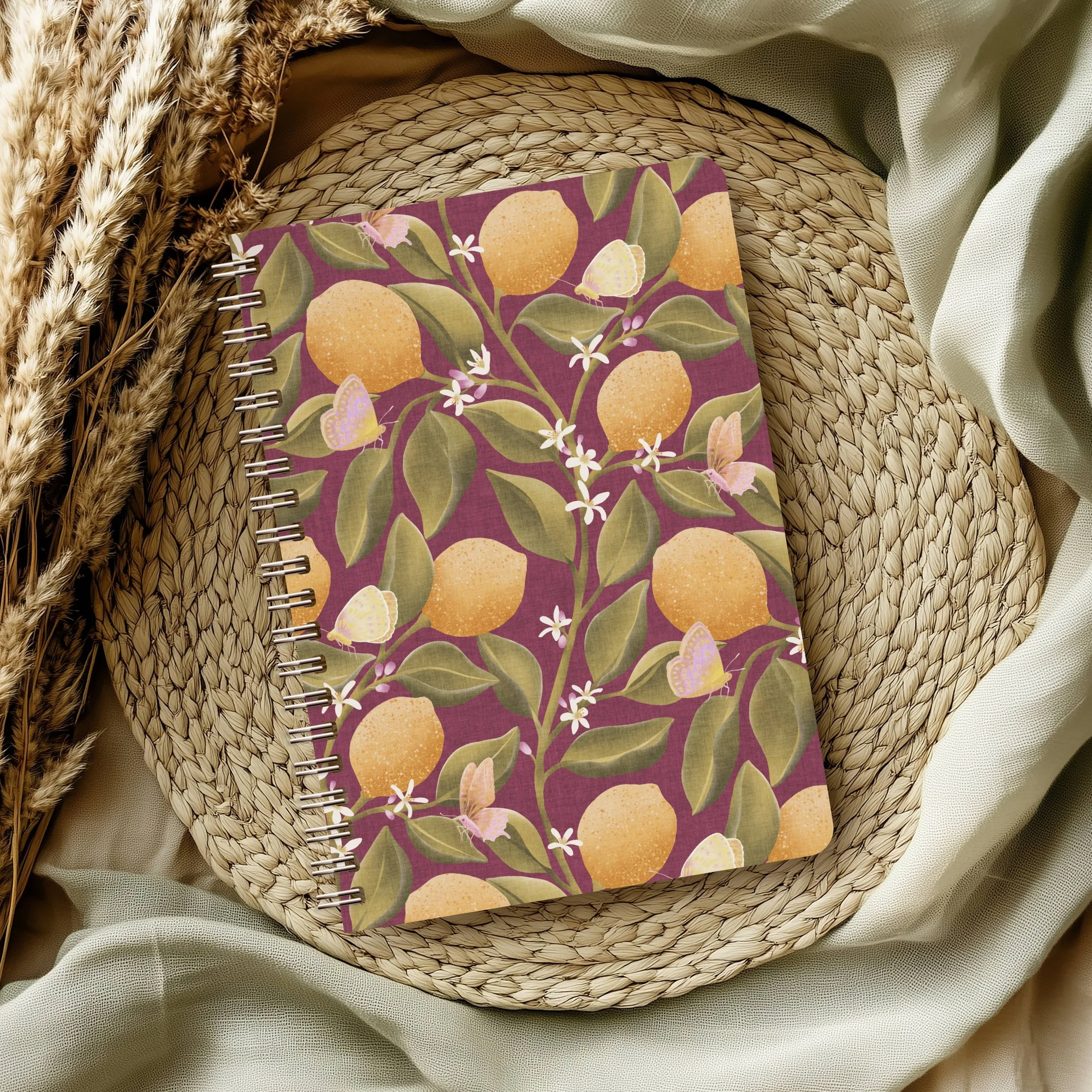 Stationery notebook planner featuring the Lemon Tree Garden botanical pattern with hand‑drawn lemons, green leaves, blossoms, and butterflies, on a warm dark red background, designed by Aitch Jay Designs.