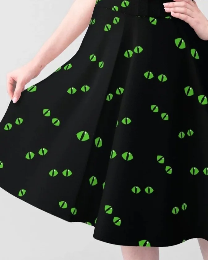 A person wearing a black skirt with a pattern of green eyes.