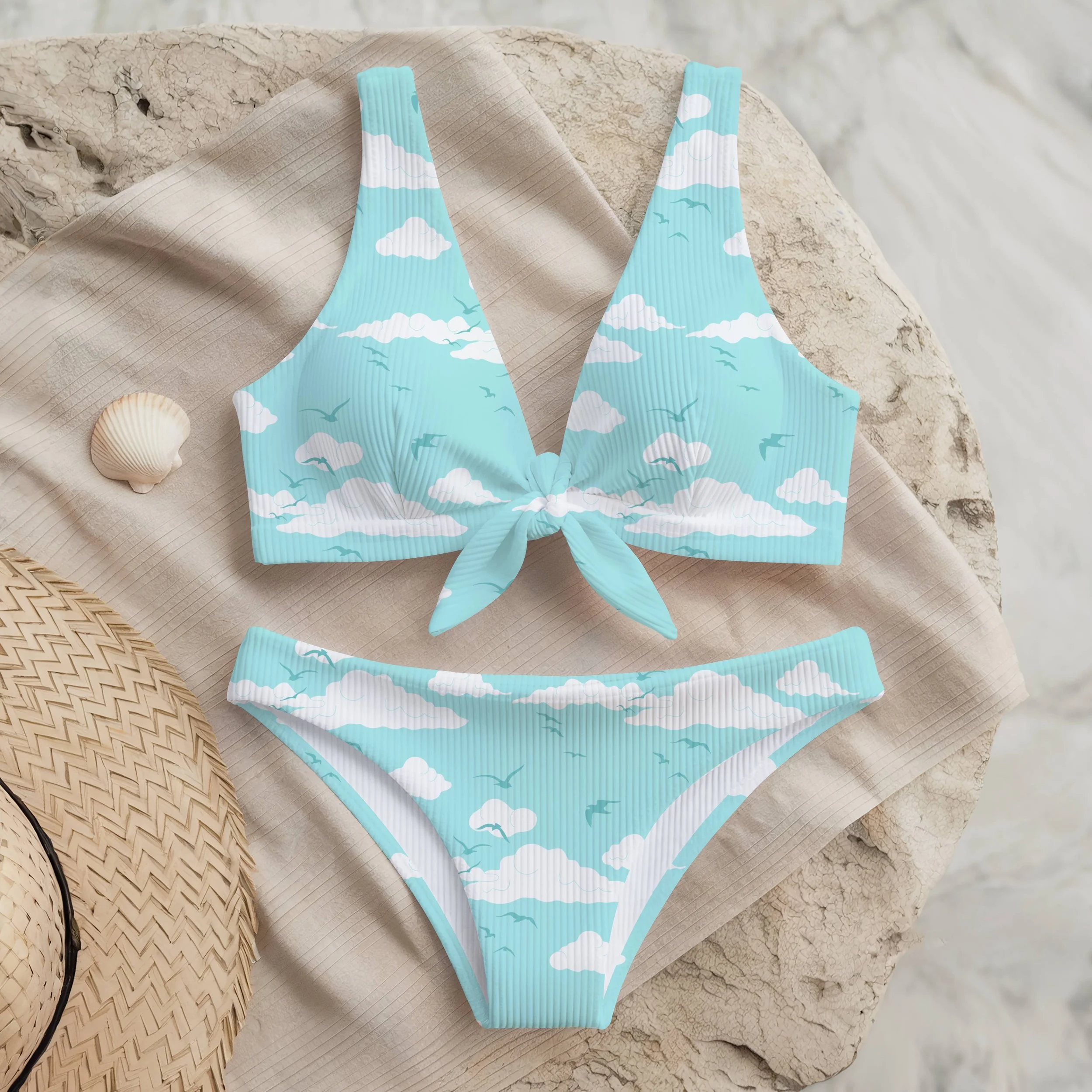 Two‑piece swimsuit showcasing a cloud‑and‑bird textile design from the Free as a Bird collection, arranged with beach accessories for product presentation. Ideal for apparel licensing, swimwear development and pattern marketing