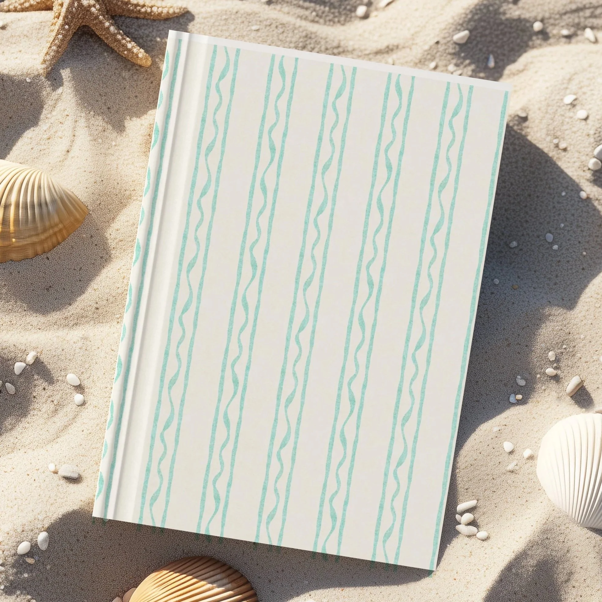 A starfish and shell on the sand with a patterned paper or towel.