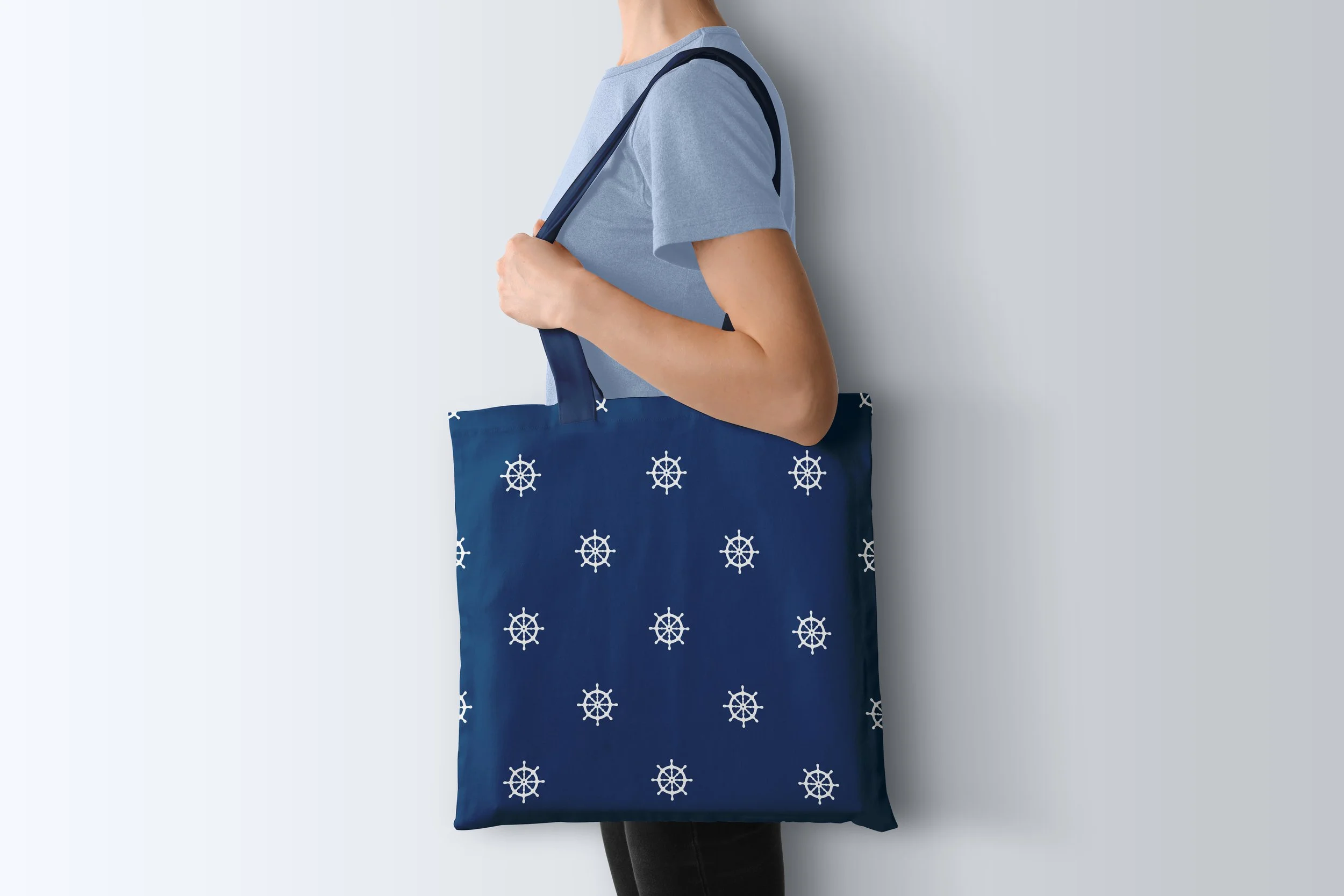 Sail Away Storybook Collection by Aitch Jay Designs — navy ship‑wheel repeat in crisp white, shown on a tote bag for a classic nautical accessory style.
