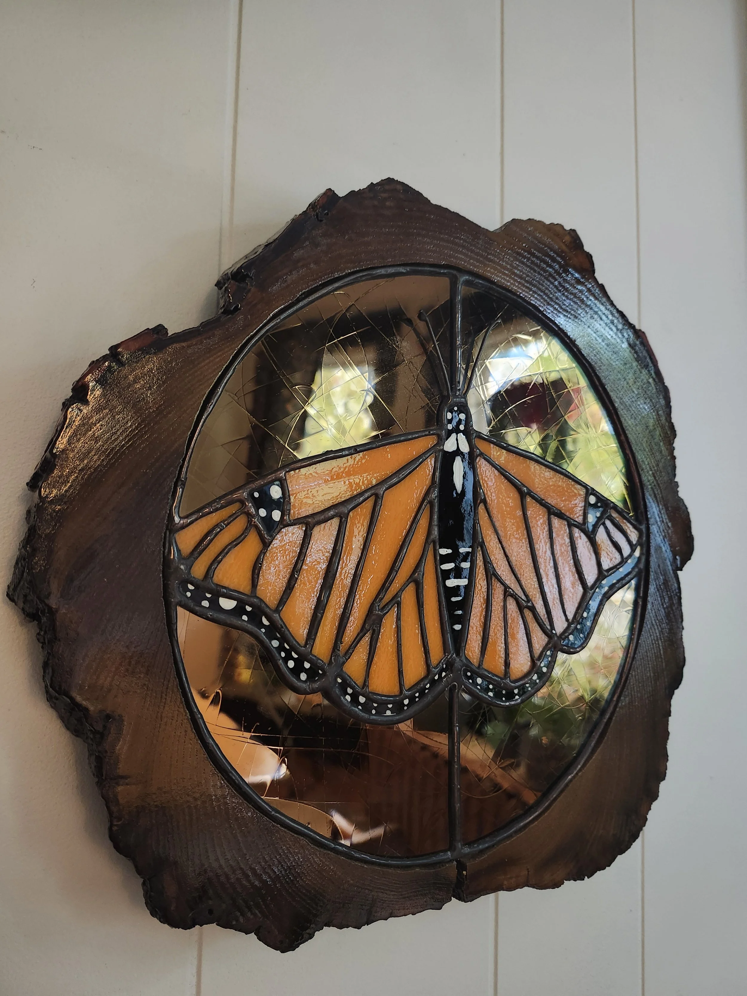 Decorative stained glass and wood wall art featuring a monarch butterfly design.