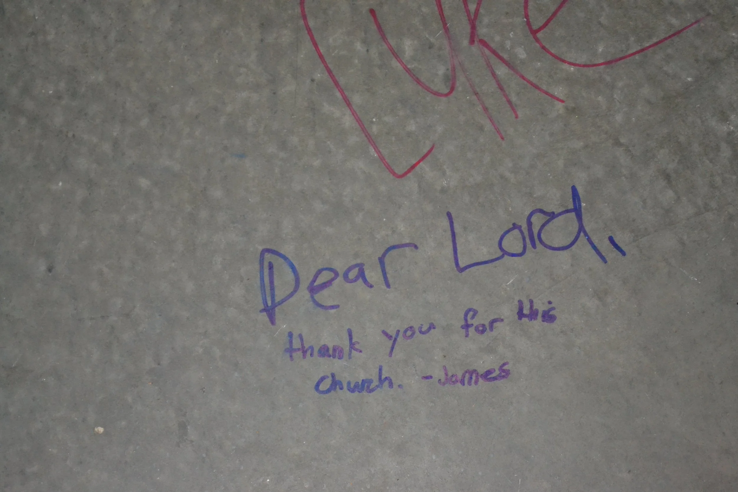 Image of handwritten "Dear Lord, thank you for this Church. - James" on the concrete in the Parish Hall.