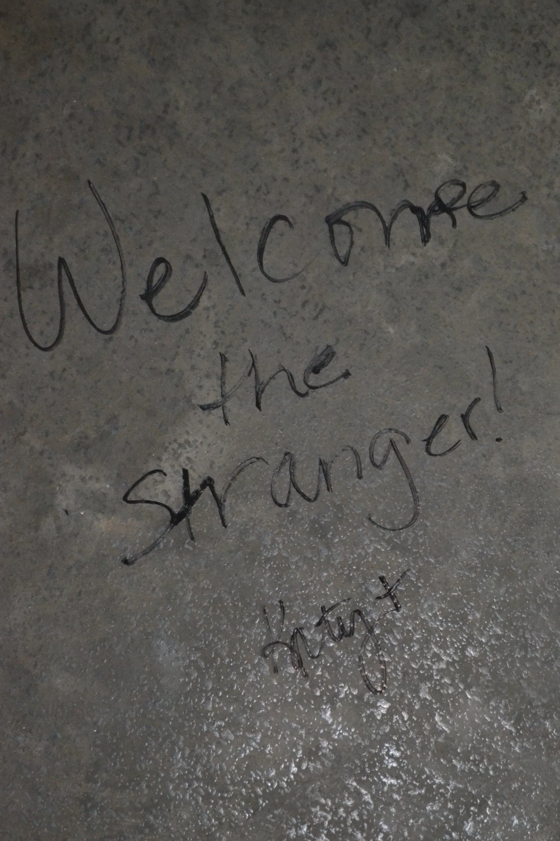 Handwritten on the concrete in the Parish Hall are the words "Welcome the Stranger" written by the Rev. Deacon Katy Smith.
