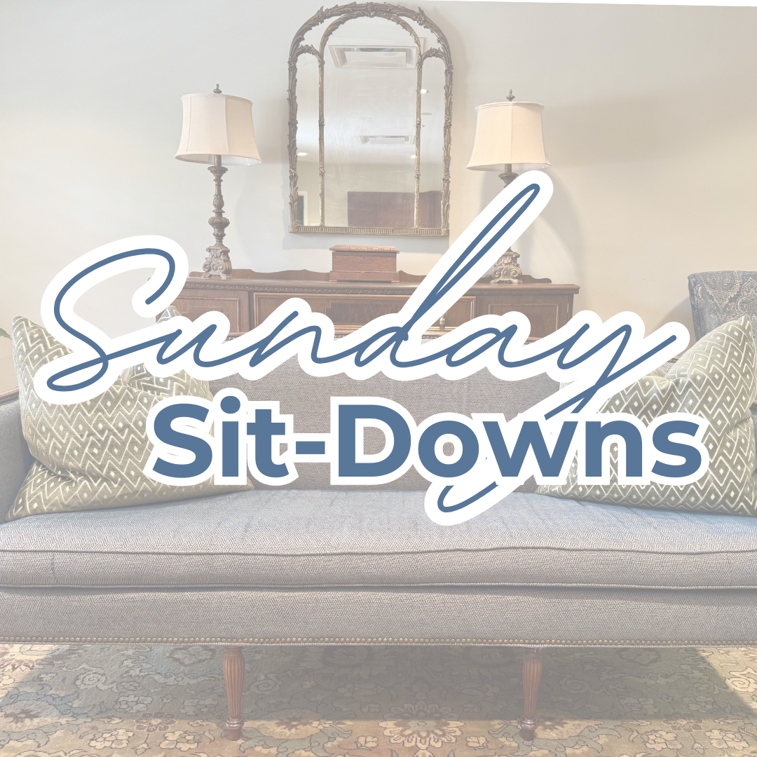 A living room with a vintage sofa decorated with patterned pillows, a wooden sideboard, a mirror, and two table lamps. Overlaid text reads 'Sunday Sit-Downs'.