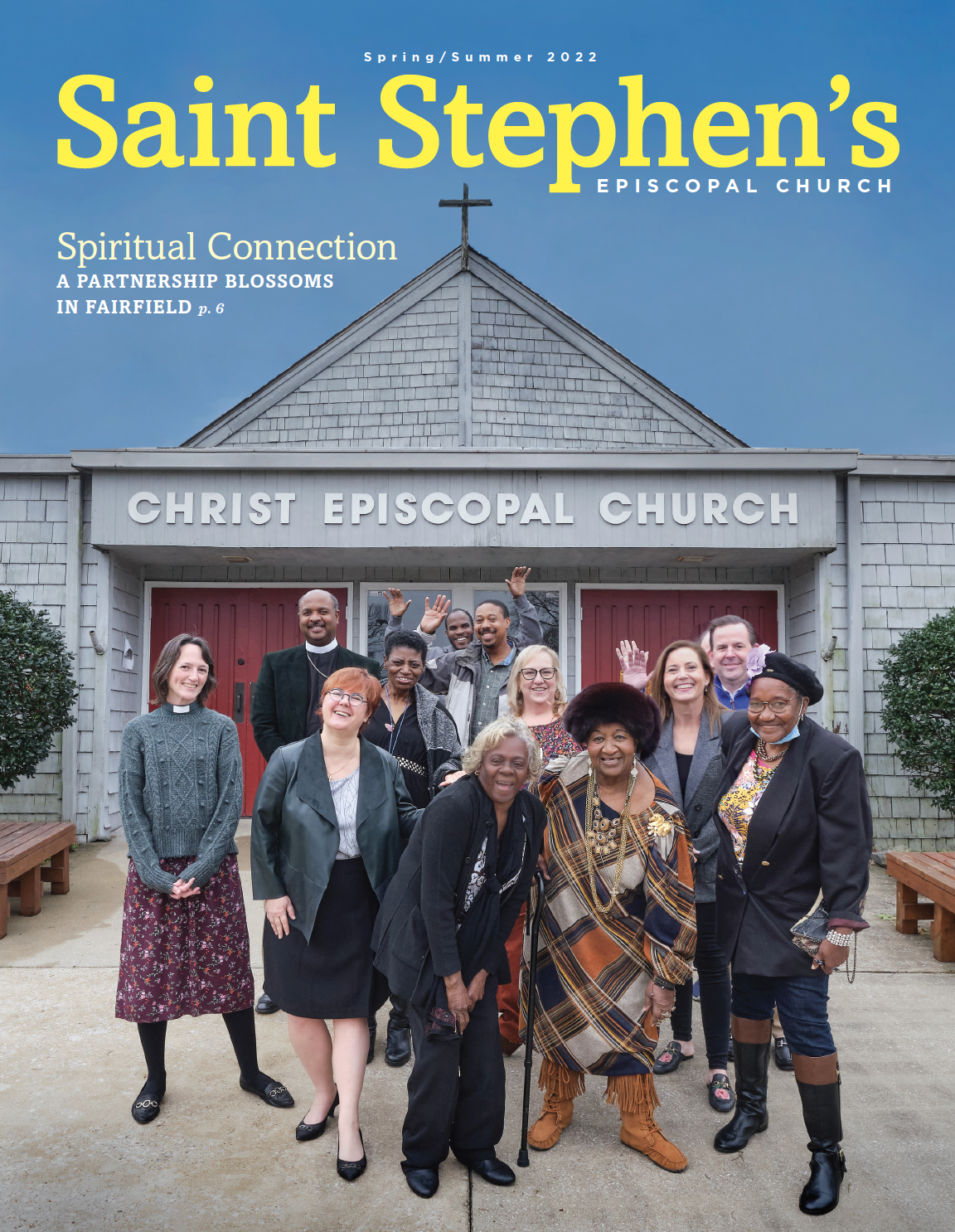 Group of diverse people standing outside Christ Episcopal Church, smiling and waving, with a blue sky background.