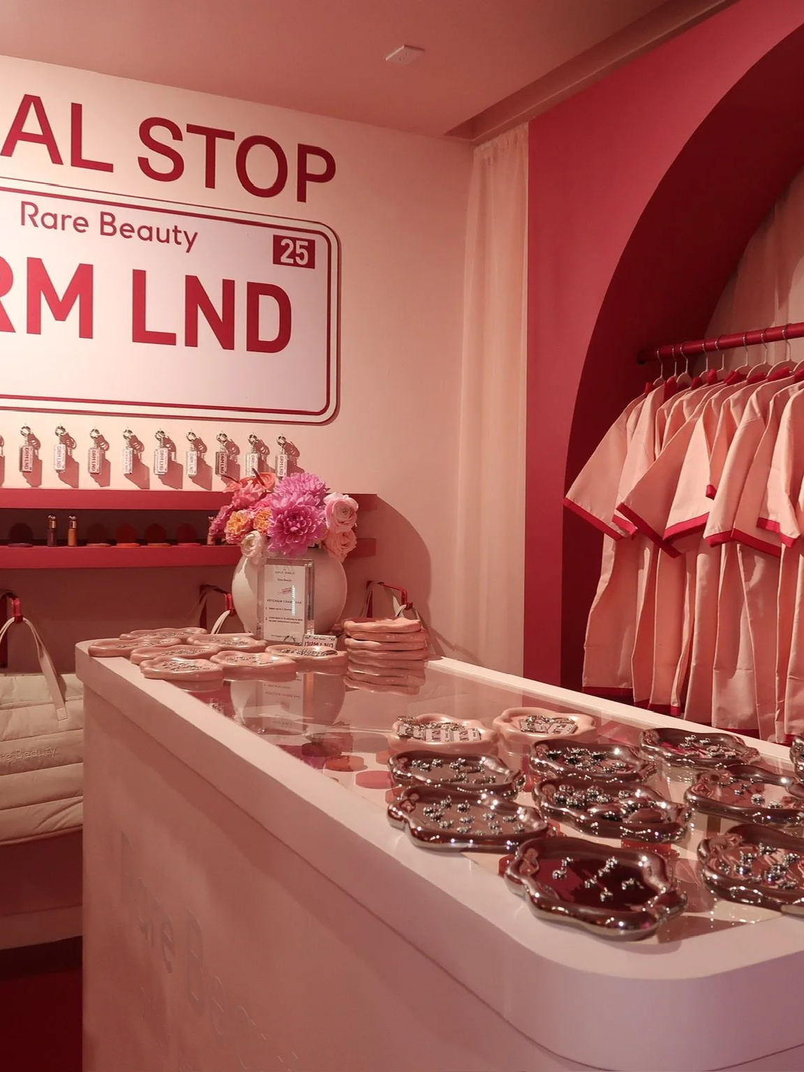 Pink-themed boutique store display with clothing, jewelry, and decorative items, featuring a pink and white color scheme and a large sign reading Rare Beauty DREAMLAND. Miami Design District custom charm bar brand activation event 