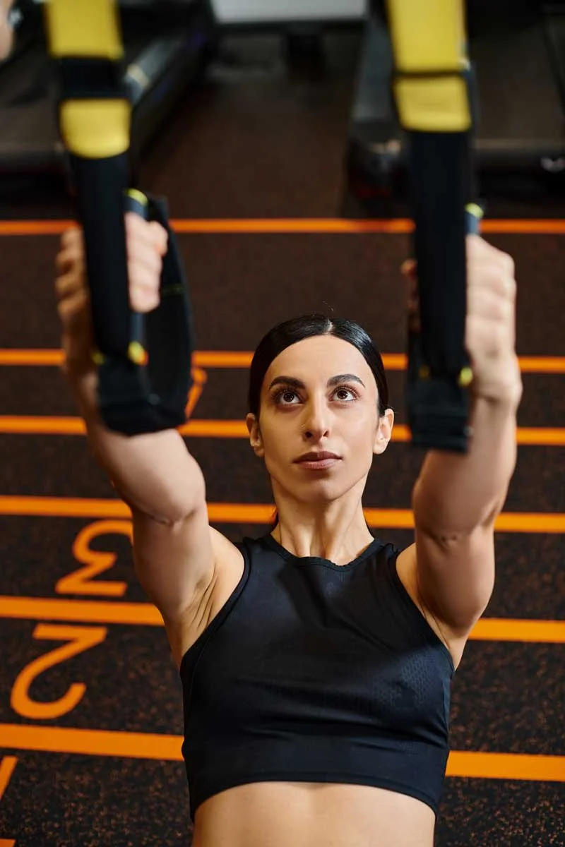 Woman performing an exercise on gymnastic rings at a gym.
