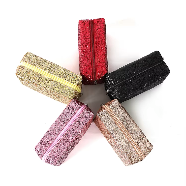 Five glittery pencil cases in gold, pink, red, black, and rose gold arranged in a star shape on a white background.