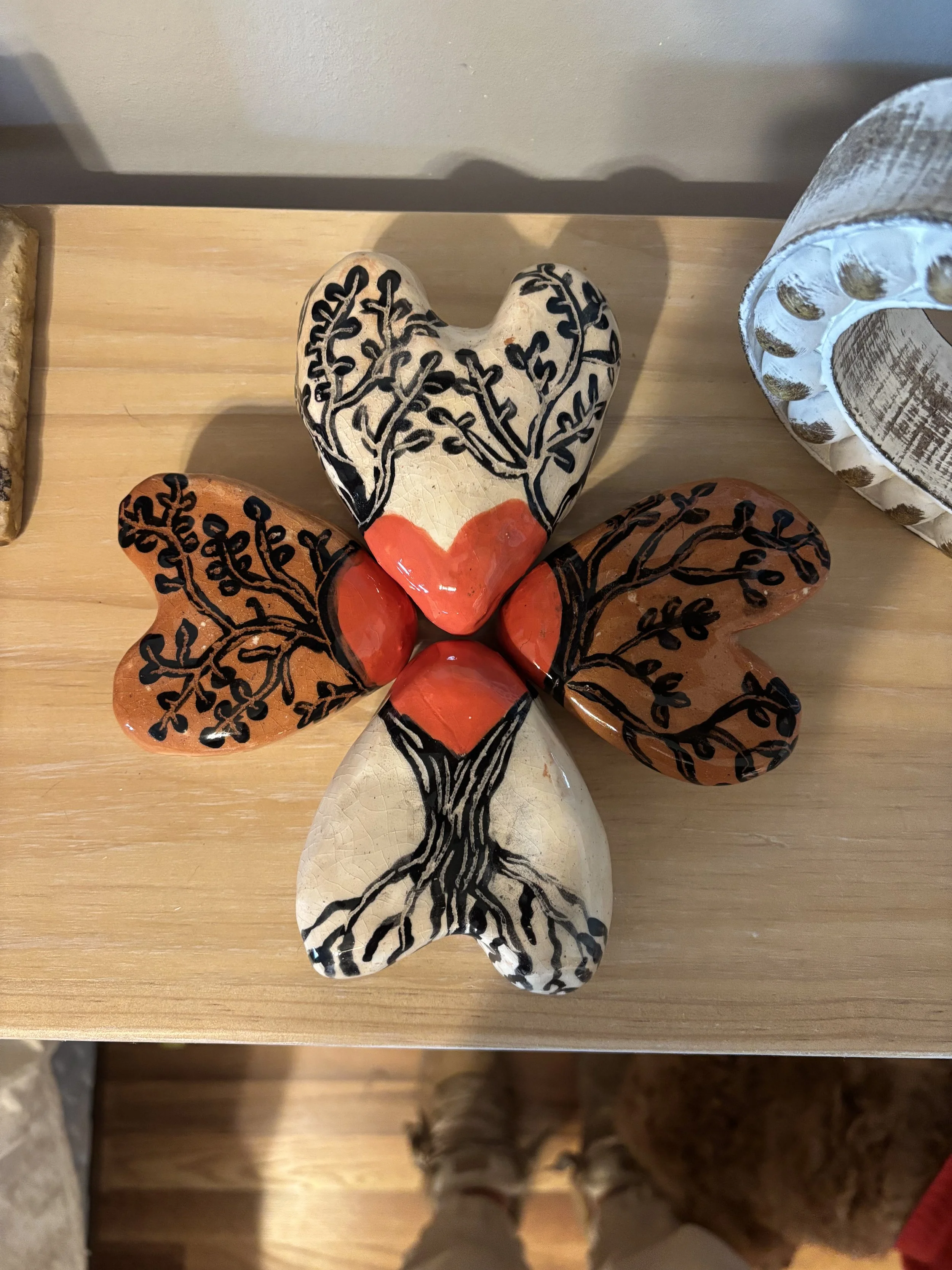 Decorative ceramic tree of love sculpture with painted black tree branch and leaf designs, featuring black, white, and red colors, placed on a wooden surface.