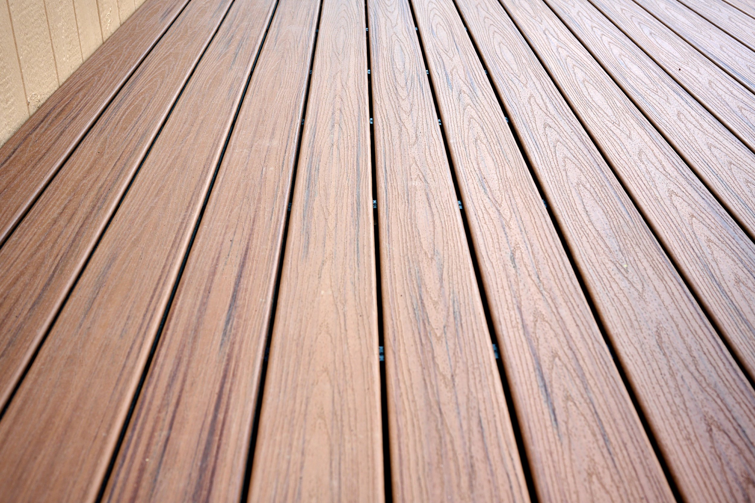 Close-up of a wooden outdoor deck with parallel planks and small gaps between them.
