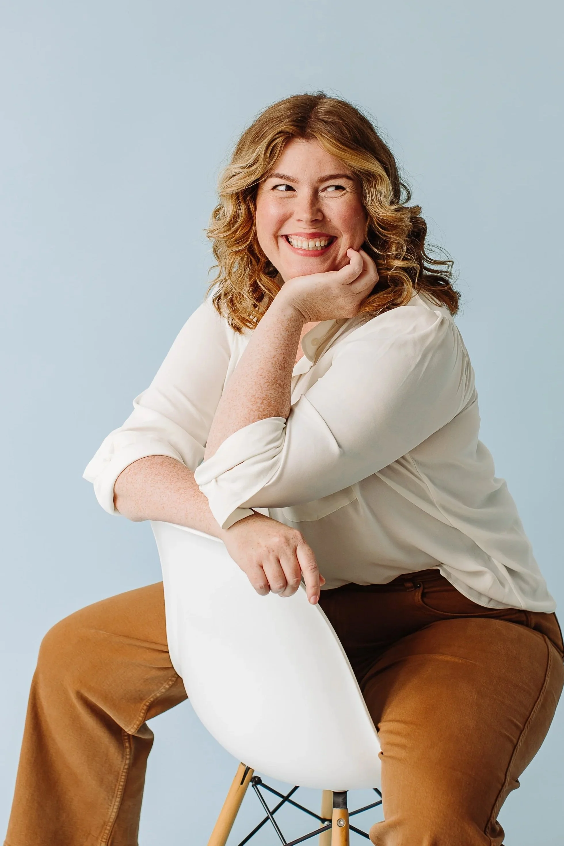 A woman with red hair sitting on a chair smiling