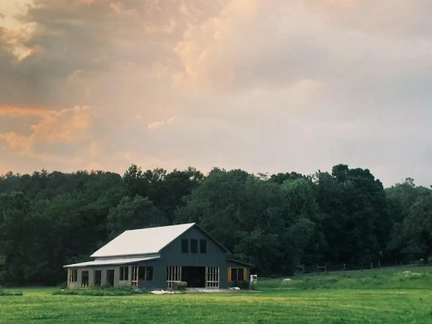 Exterior view of The Reserve at Two Horses Farm barn, surrounded by manicured green pastures in Morganton, North Carolina at sunset