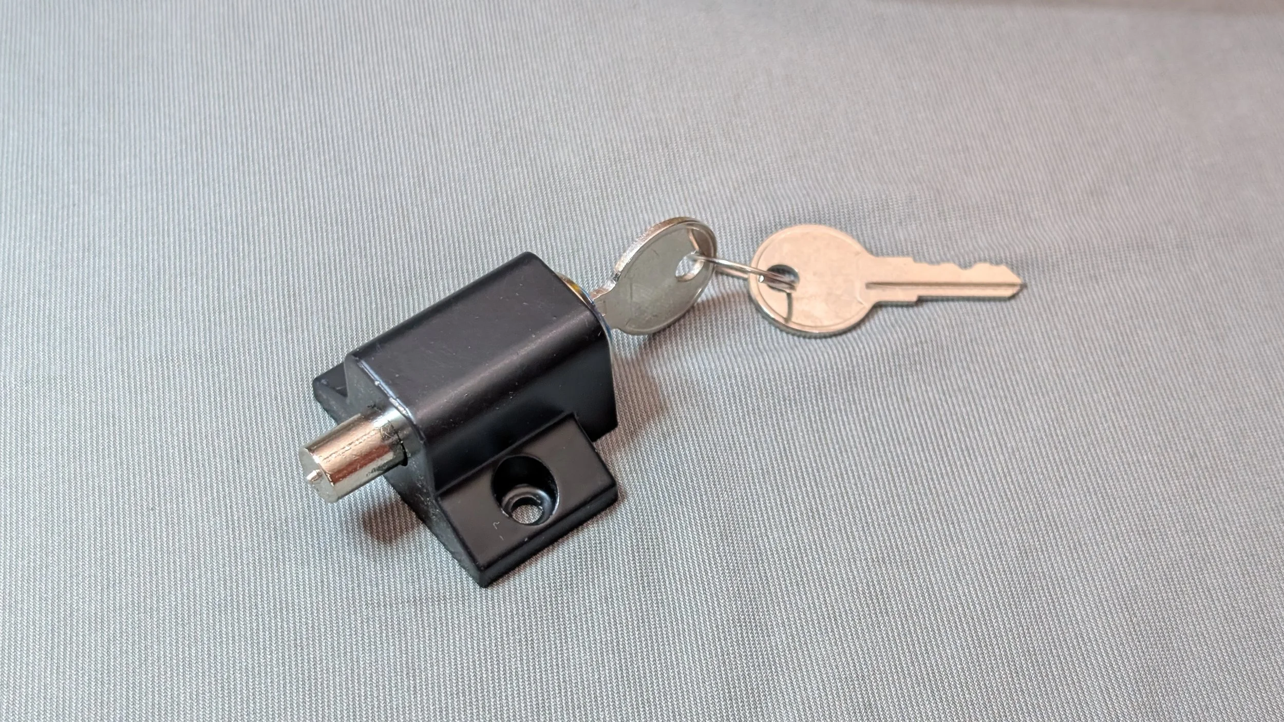 A close-up of a black door lock with a silver key inserted into the lock.
