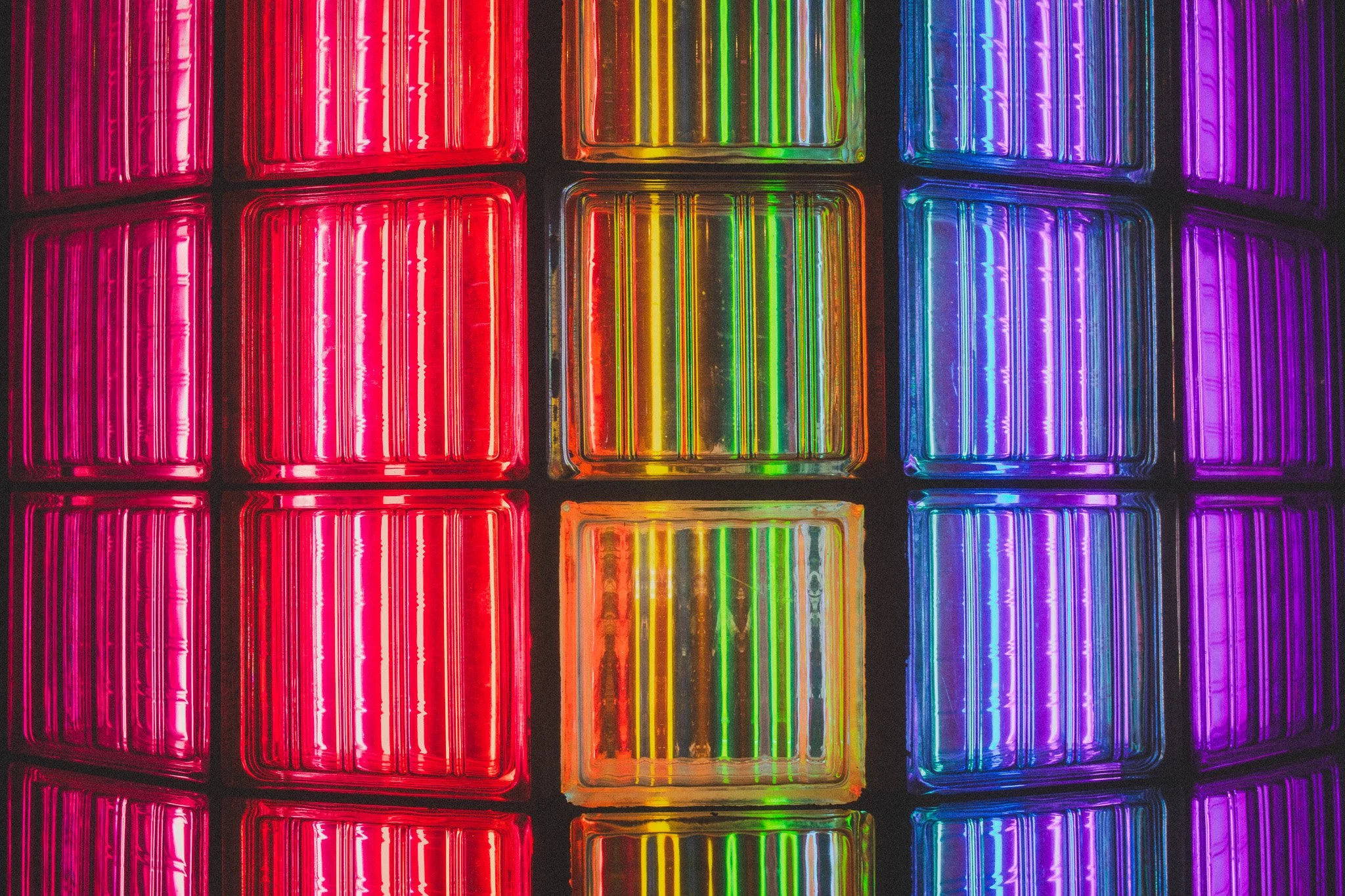 Close-up of colorful glass blocks illuminated with neon lights in red, yellow, green, blue, and purple.