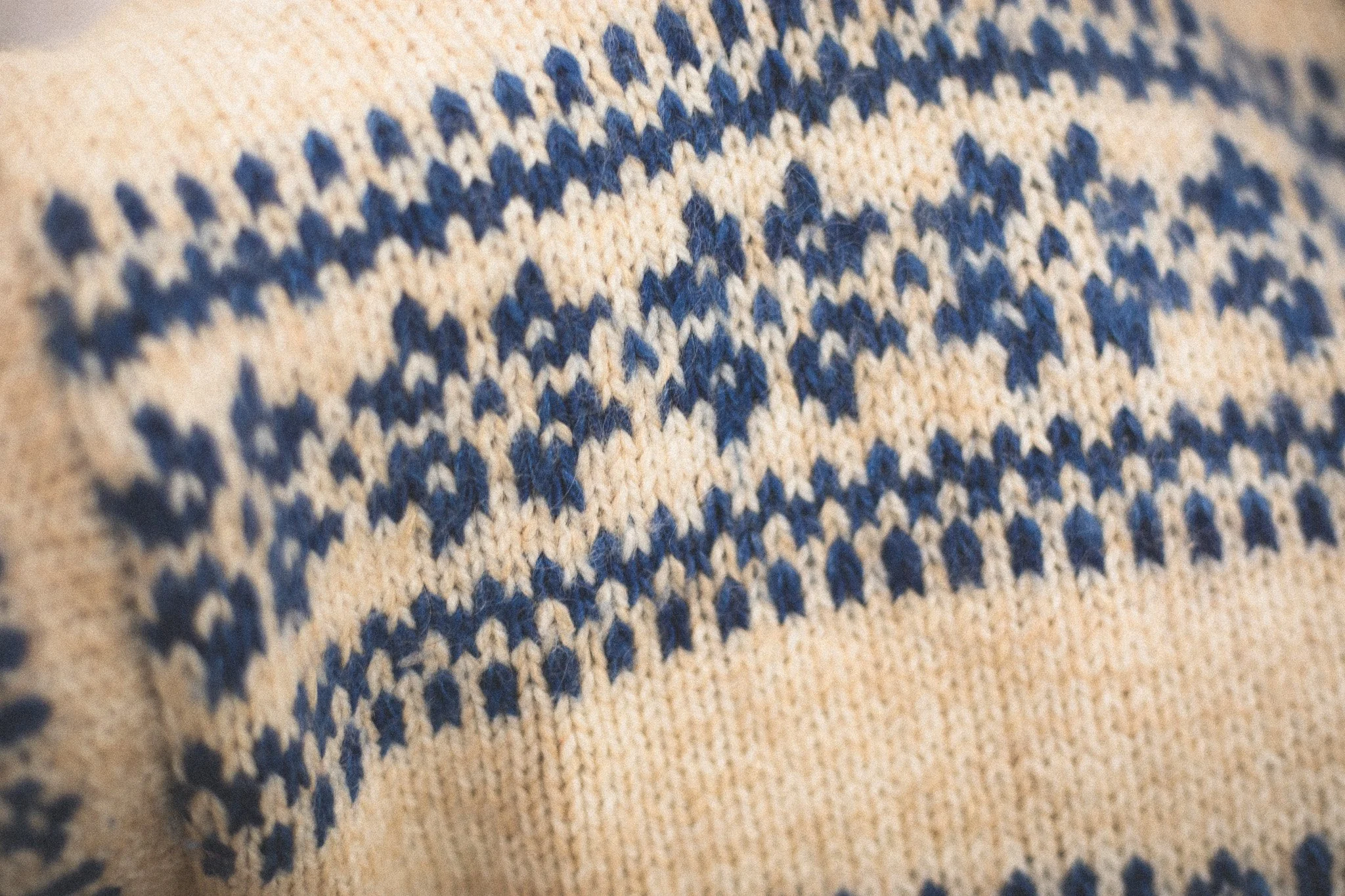 Close-up of a knitted fabric with a pattern of blue and beige yarn.