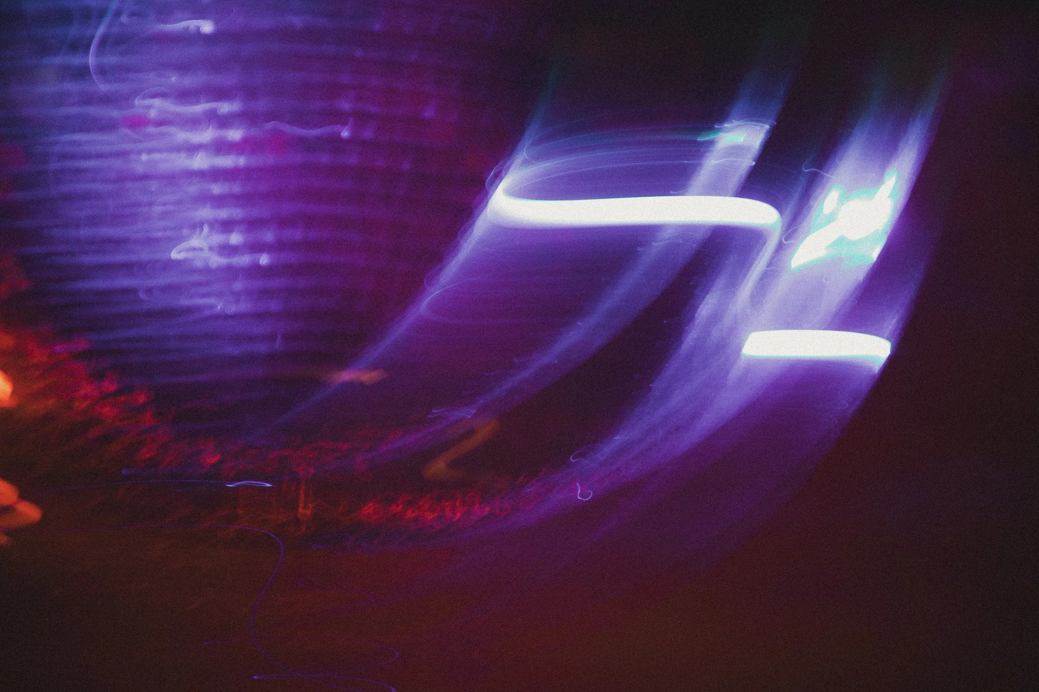 Abstract long exposure photograph of moving purple and white neon lights at night.