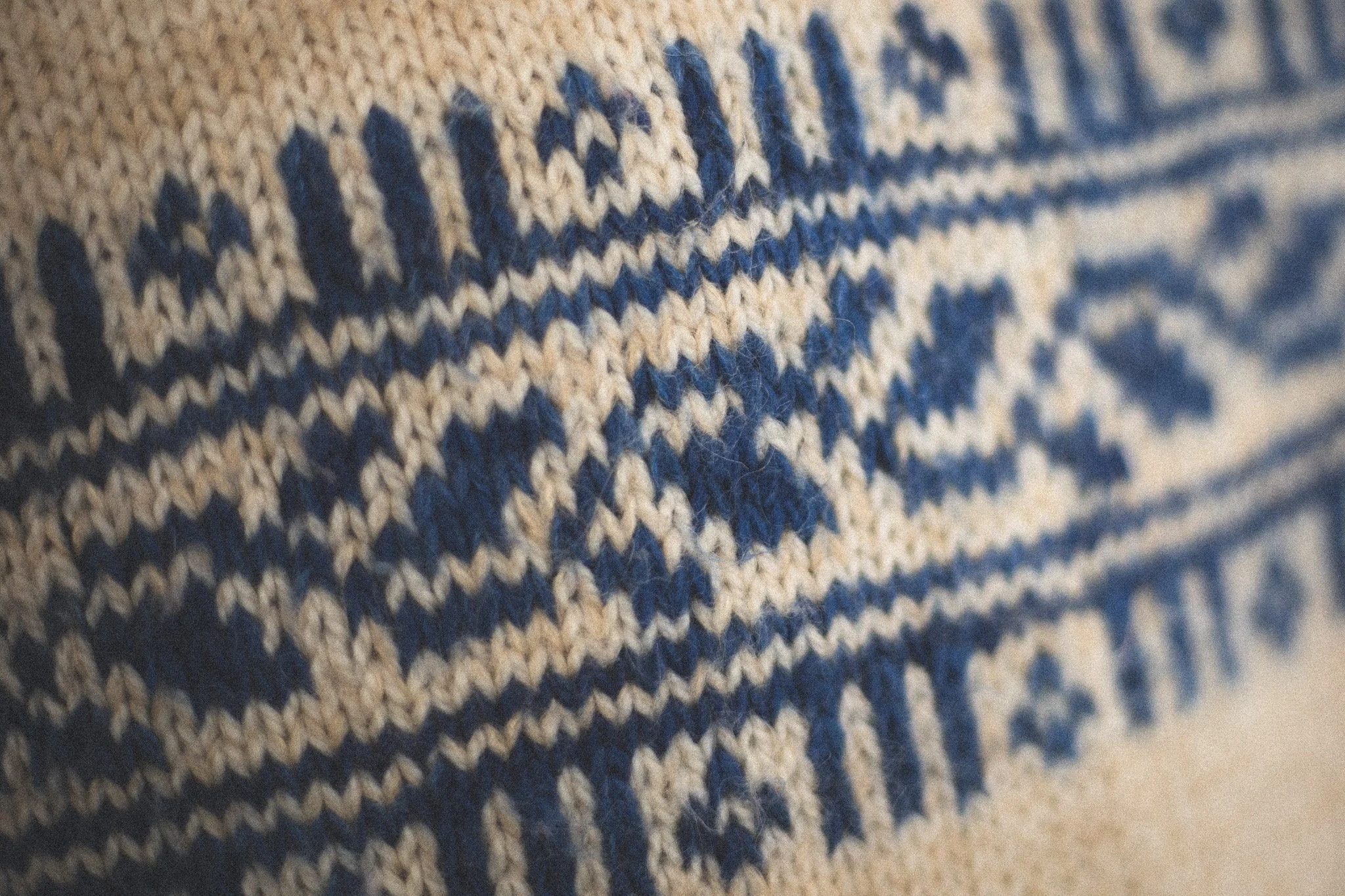 Close-up of a knitted textile with a pattern in blue and beige colors.