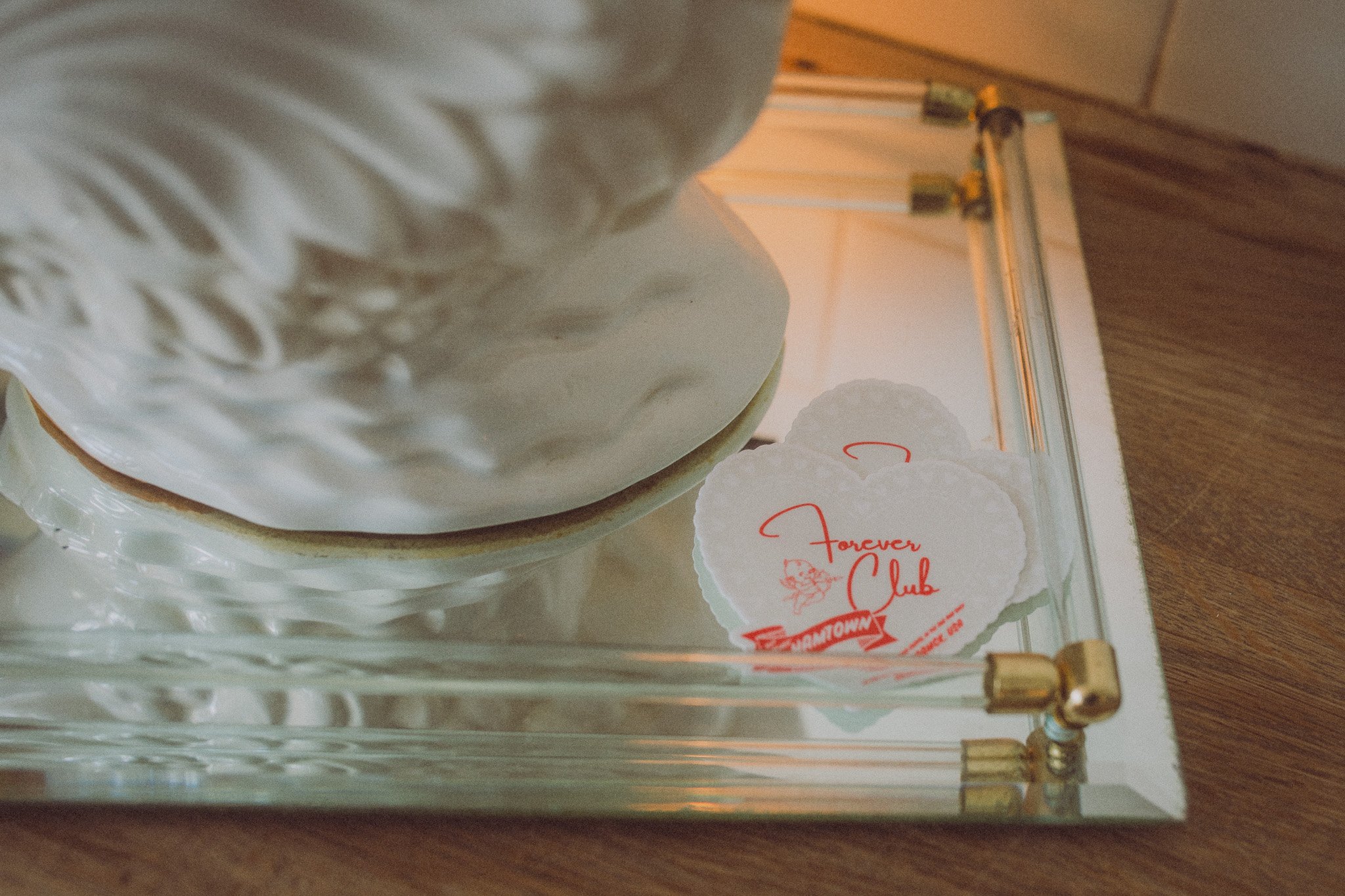 A glass display case with heart-shaped notes that read "Forever Club" inside, placed on a wooden surface.
