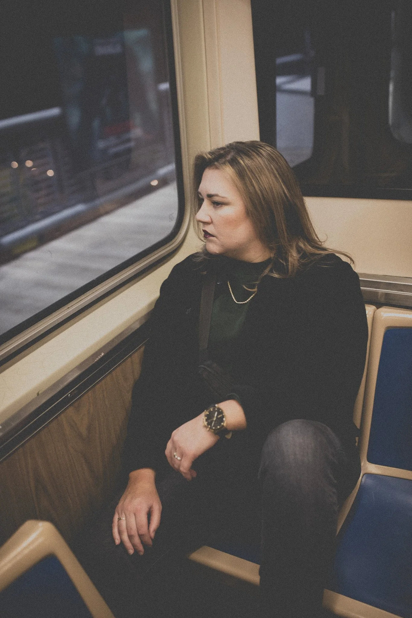 A woman sitting alone on a train, looking out the window.