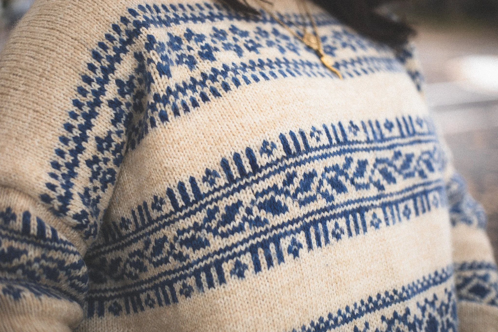 Close-up of a cream-colored sweater with blue geometric and Nordic-style patterns.
