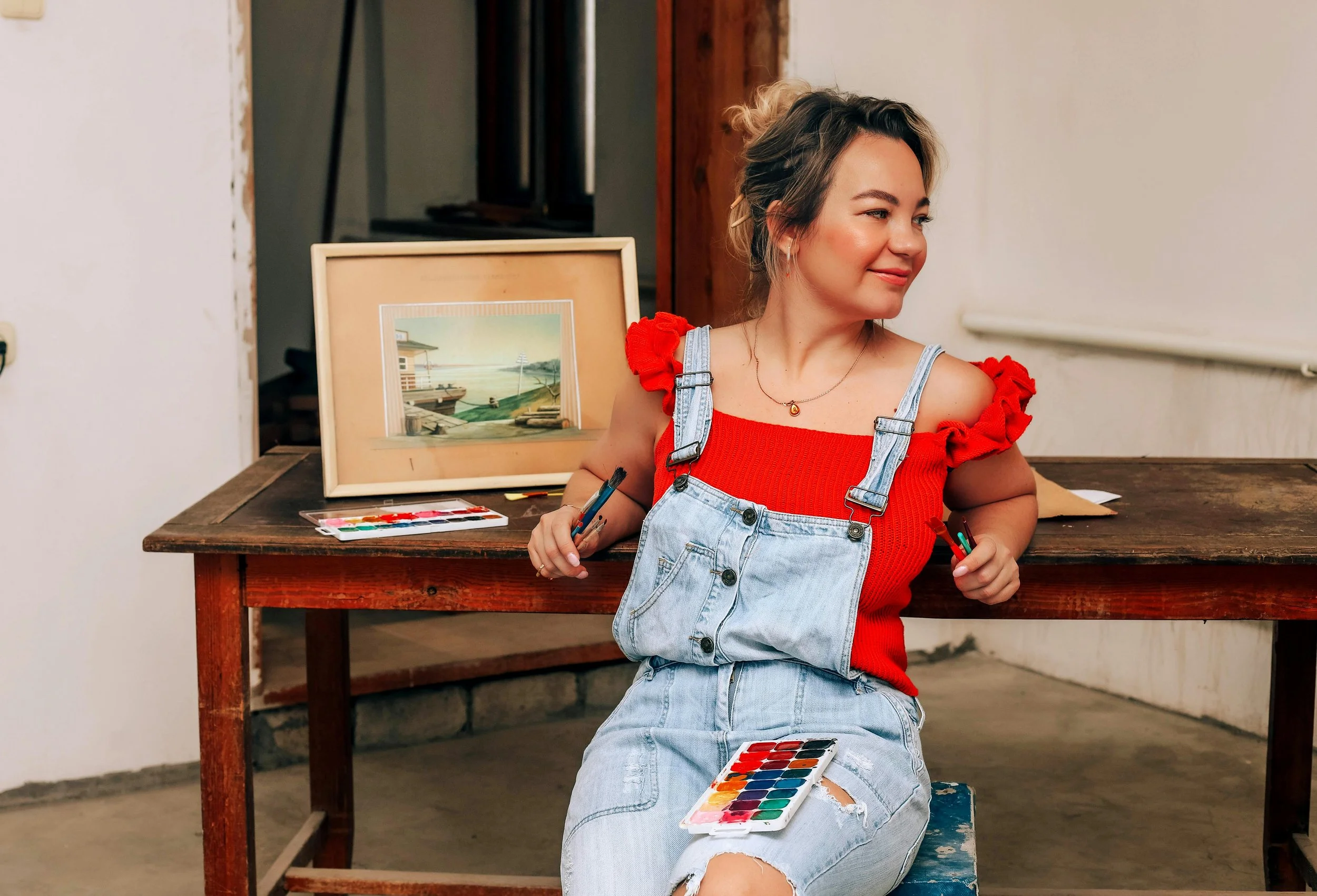 Scenic landscape of a lake surrounded by rolling green hills and distant mountains under a cloudy sky.