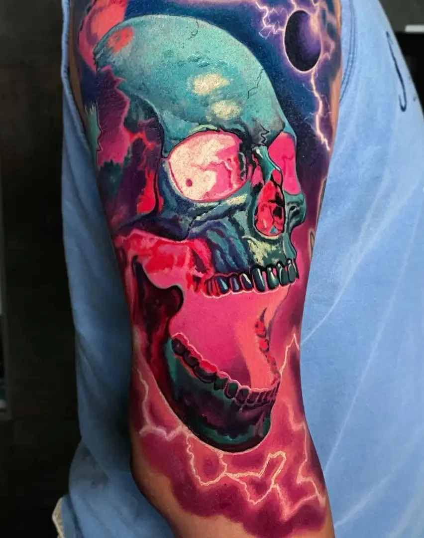 Colorful tattoo of a skull with neon-like shades, lightning, and a dark background on a person's upper arm.