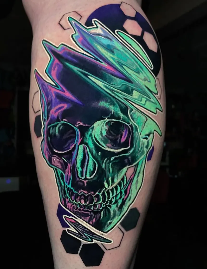 Colorful tattoo of a skull with vibrant shades of green, purple, and blue, surrounded by hexagon shapes and abstract lines.