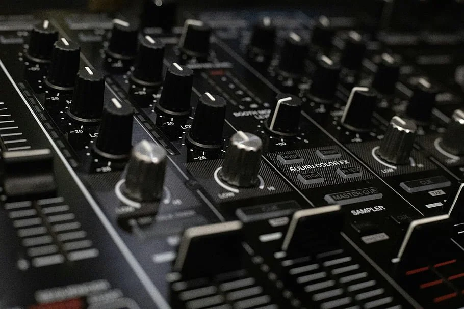 Close-up of a professional DJ or audio mixing console with knobs, sliders, and buttons.